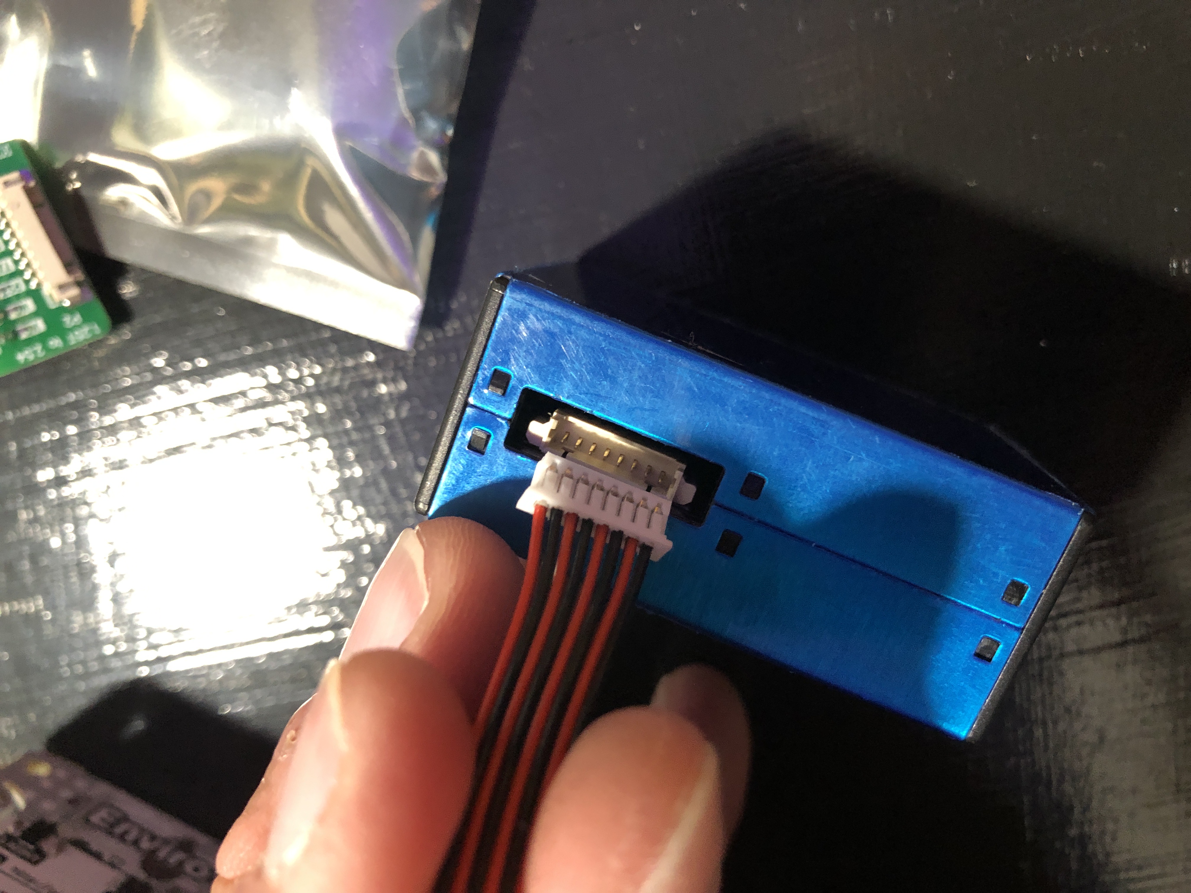 Plug the ribbon cable into the blue PMS5003 Sensor with the side of the plug with the lines/metal up perpendicular to the pins closest to the edge.